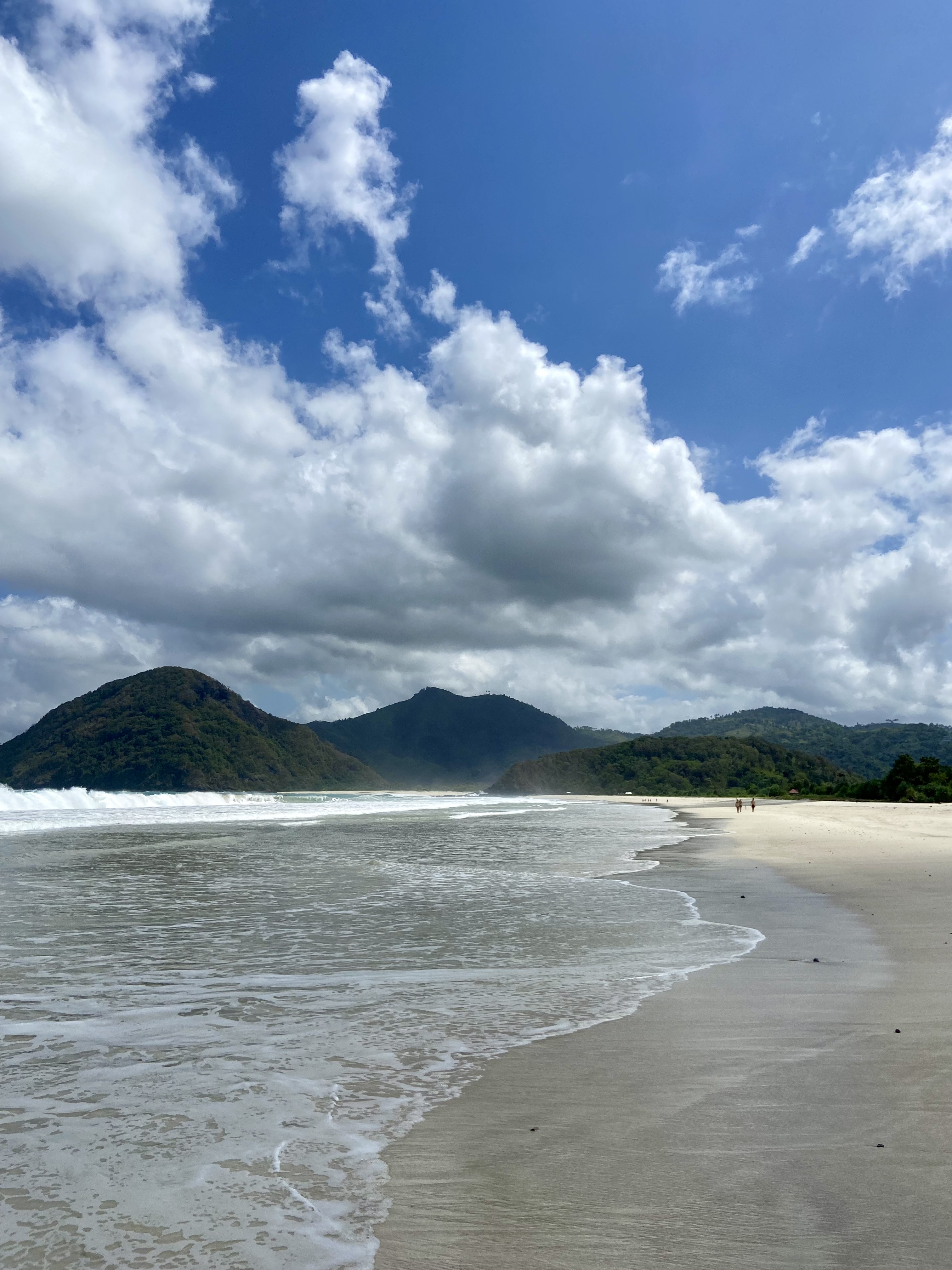 Spiaggia tropicale di Lombok con mare turchese e montagne sullo sfondo, ideale per relax e surf in Indonesia.